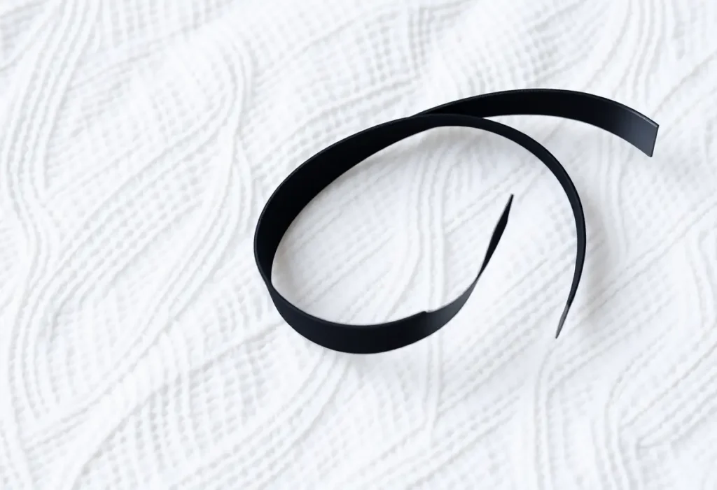 Une bande élastique noire posée sur un linge blanc, soulignant sa flexibilité et sa durabilité, lien avec l'article sur les soutiens-gorges sans bretelle.