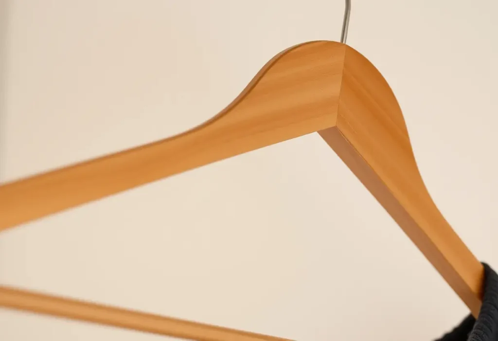 Un cintreuse en bois dans un placard, éclairée naturellement, sans texte, édition féminine.