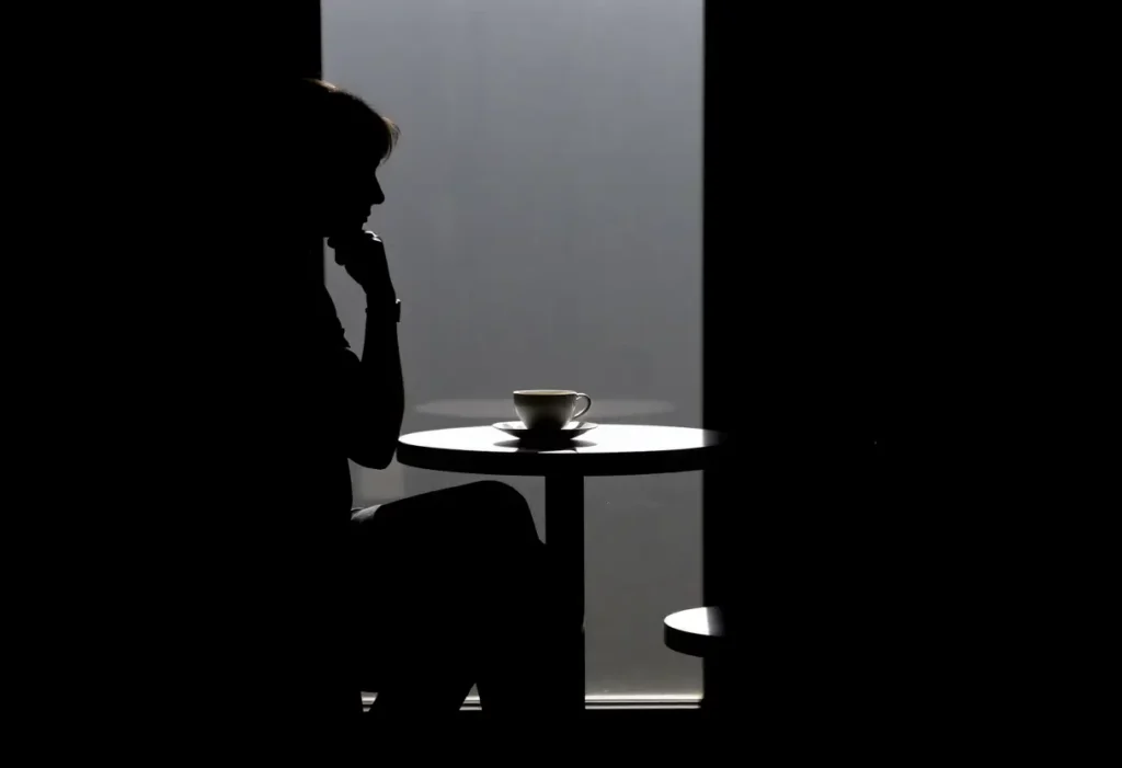 Silhouette assise à une petite table ronde avec une tasse et une soucouche en porcelaine blanche