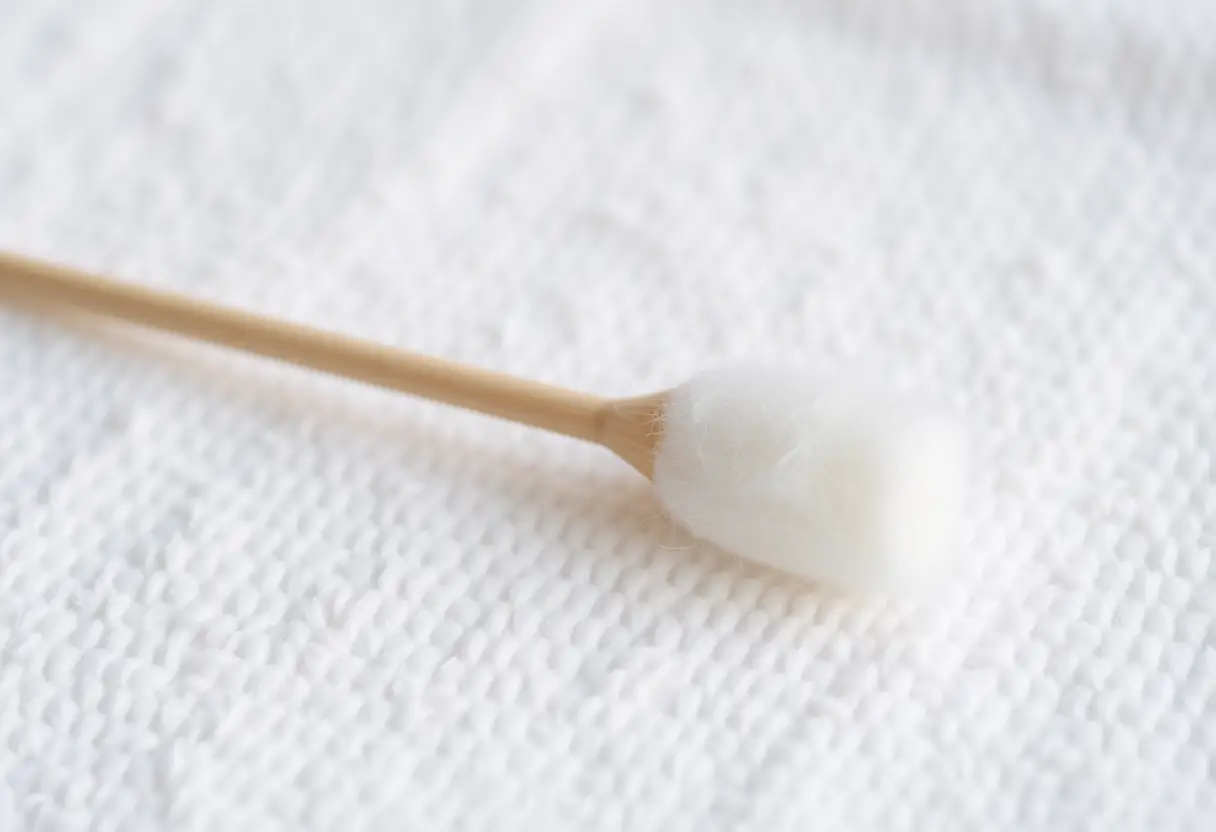 Un coton-tige posé sur un linge blanc, symbolisant le soin et la douceur.