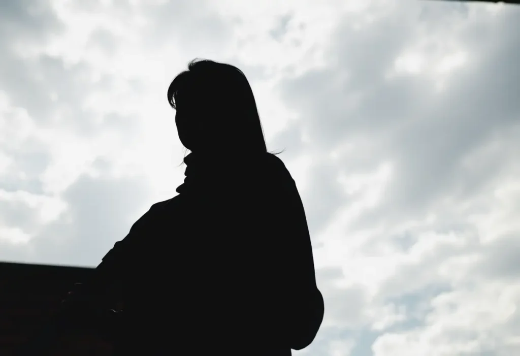 Un profil flou d’une femme tenant un règle en bois contre un mur en brique